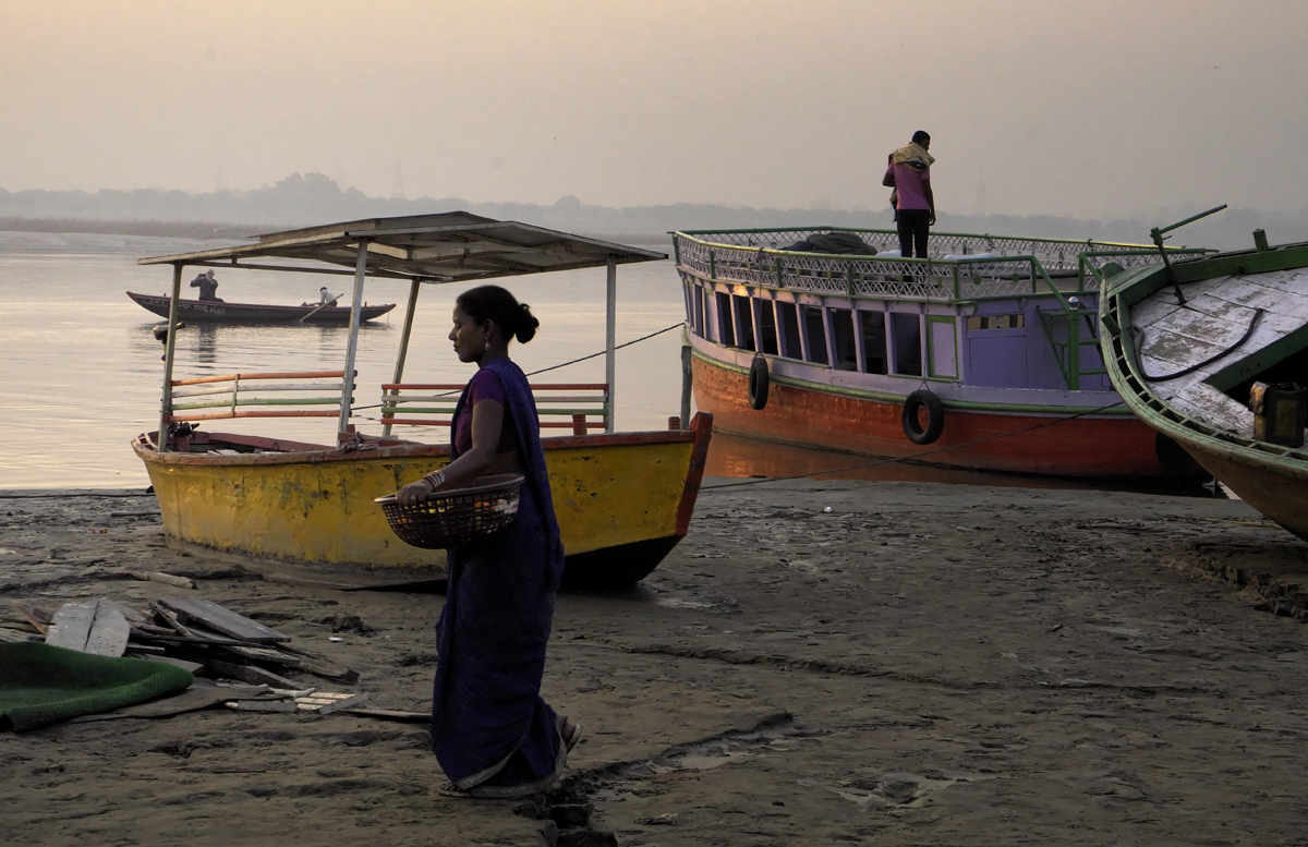 Street photography, River shore, woman, basket, sari, boats, misty morning, Varanasi, India