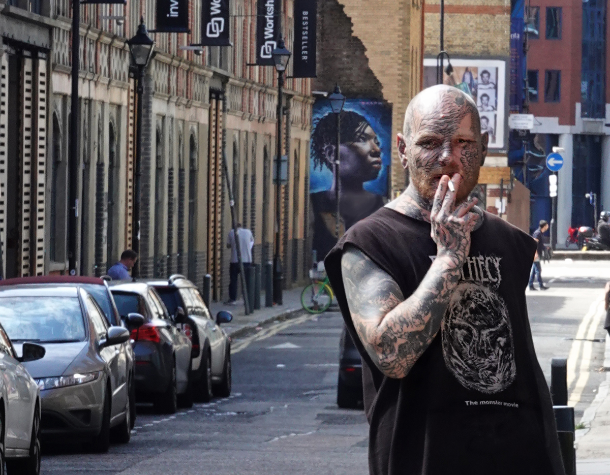 Street photography, tattooed man, smoking, cigarette, East London, street art, mural, UK