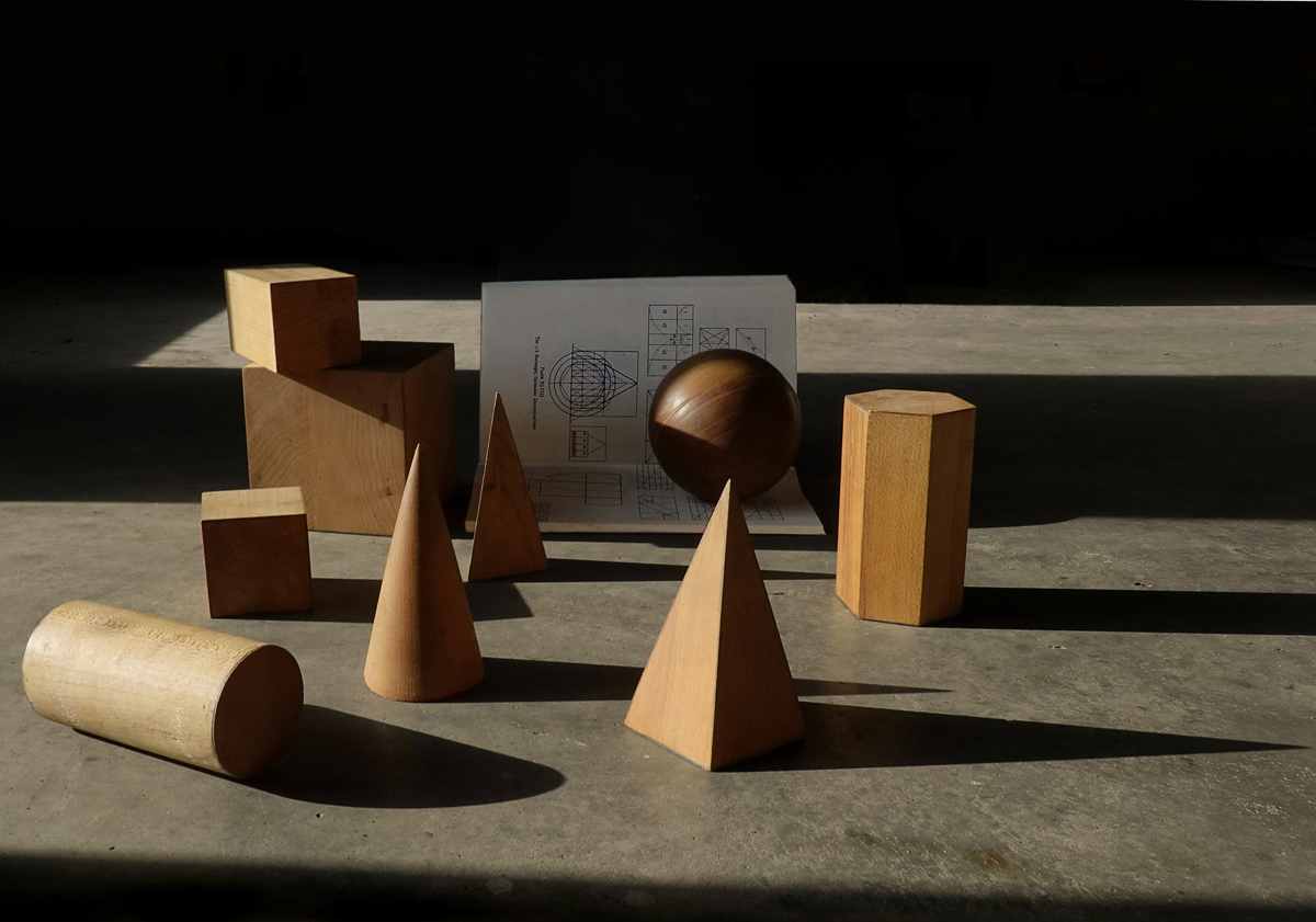 Still life, geometric forms, pyramid, cube, cylinder, sphere, wooden blocks, geometry book, shadows